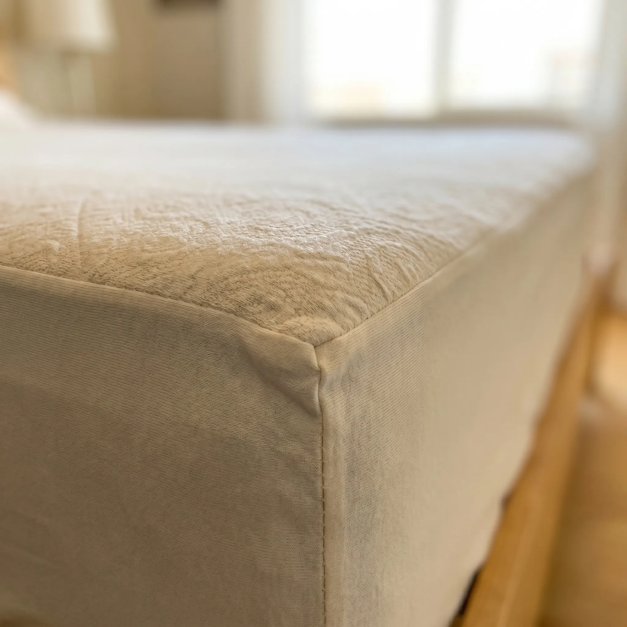 Cotton knit mattress protector seam close up where ticking meets cotton jersey skirt
