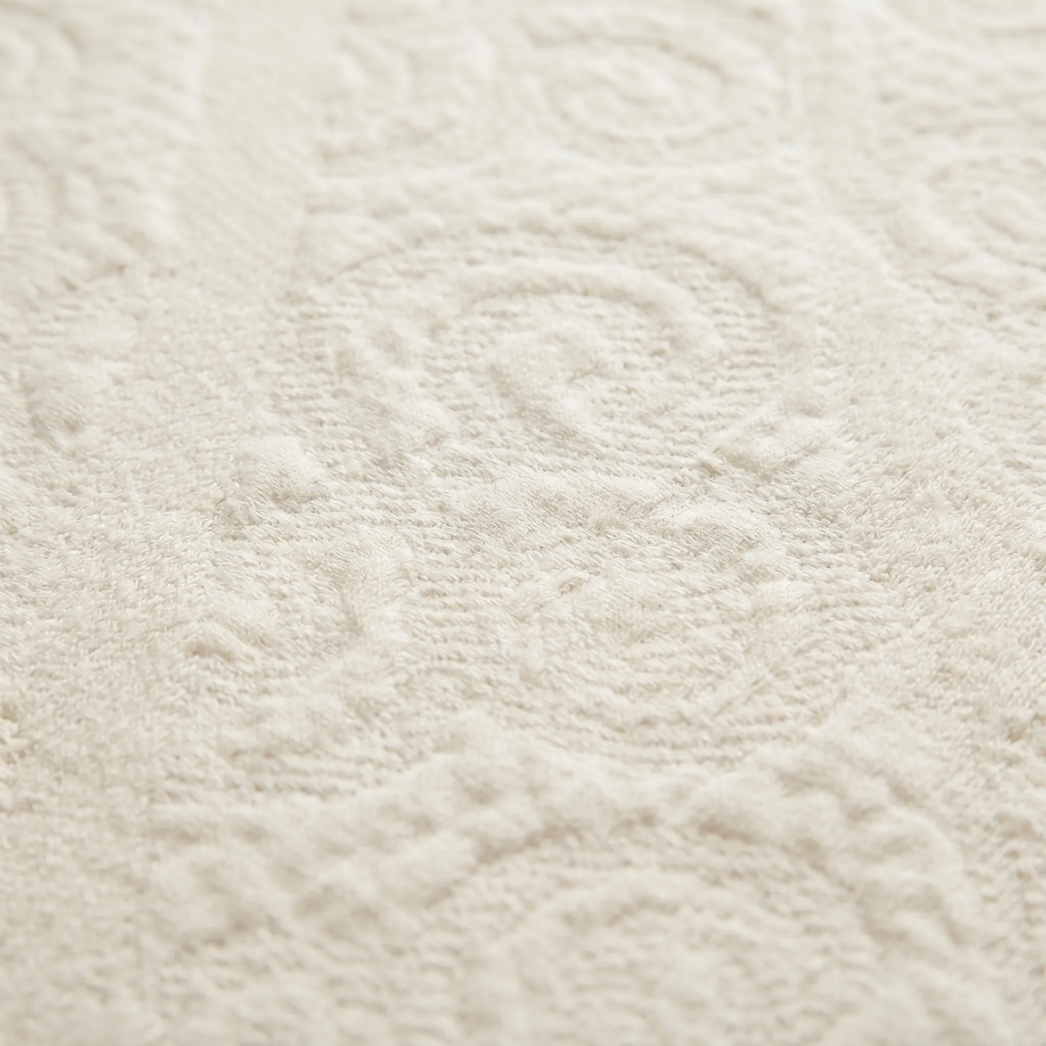 Organic cotton double knit ticking macro showing embossed jacquard medallion pattern