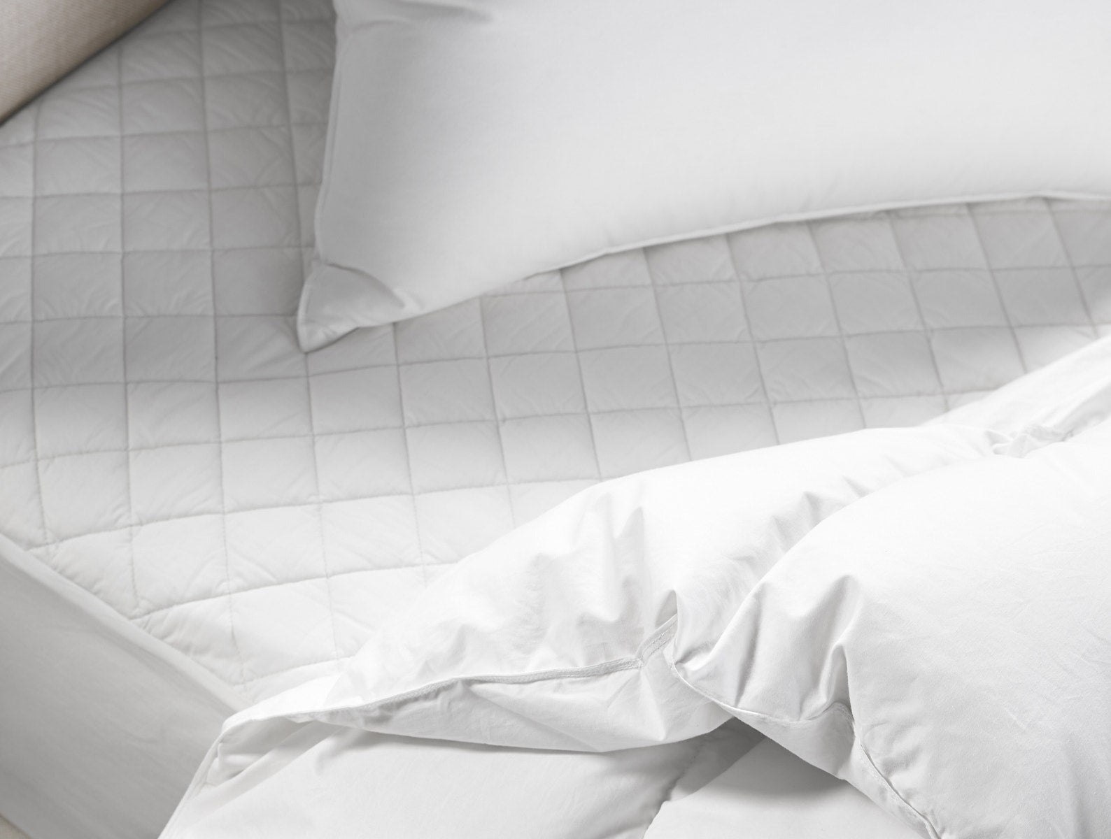 Organic cotton mattress pad folded on bedding showing the percale face
