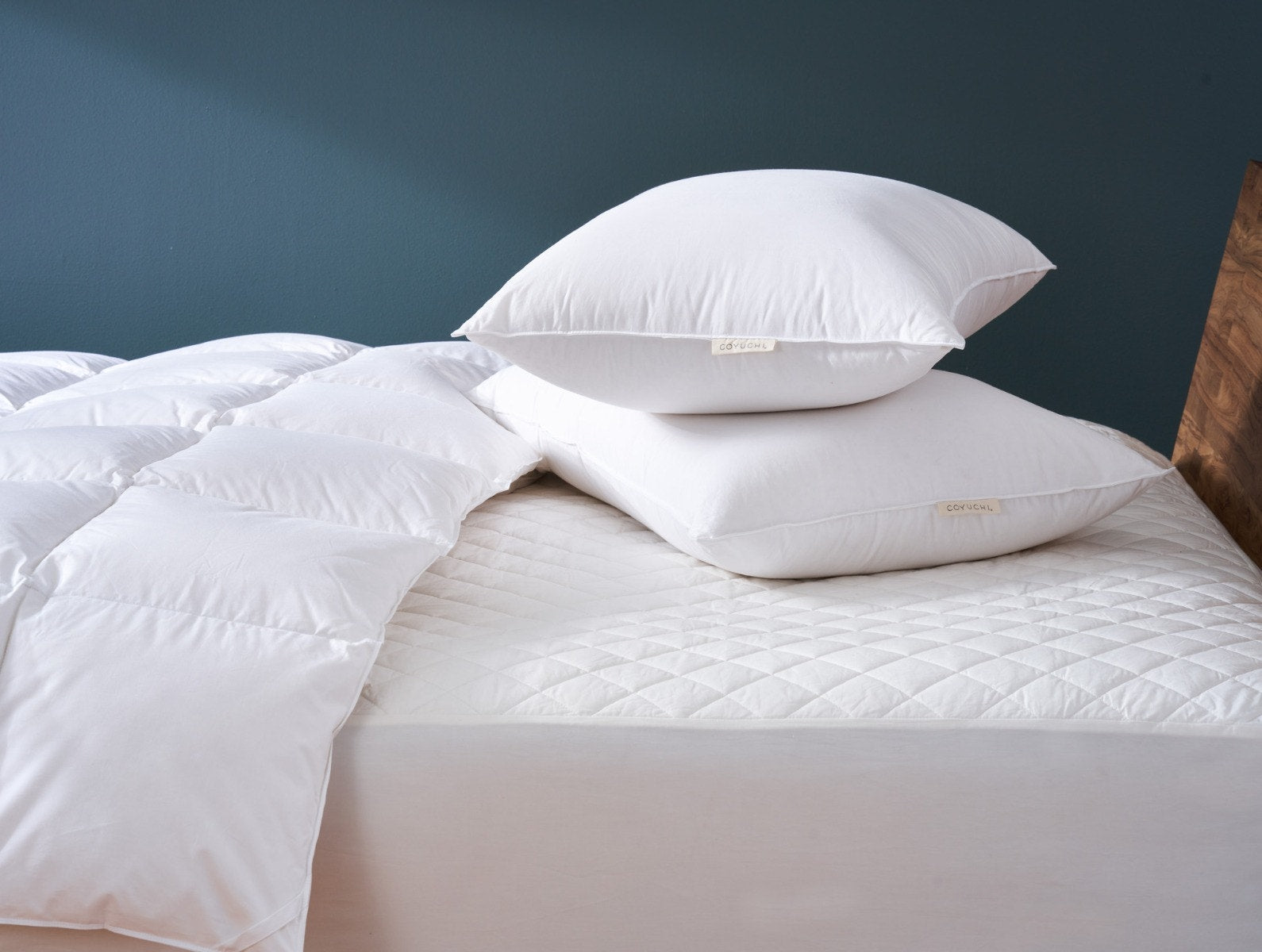 Organic cotton mattress pad dressed on a wood-frame bed in a sunlit bedroom