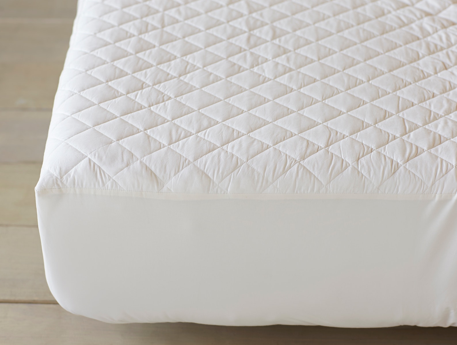 Detail of organic cotton mattress pad showing two-inch quilted squares in soft white percale