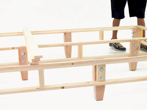 Heavy-duty foundation assembly step 19: Lay the first slat over the side-rail legs.