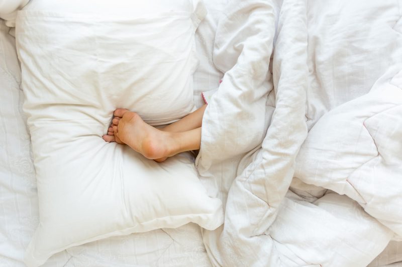 woman sleeping with legs elevated on pillow