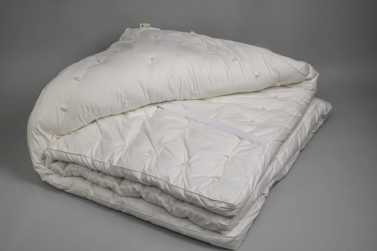 Natural wool mattress topper on bed with organic cotton sheets