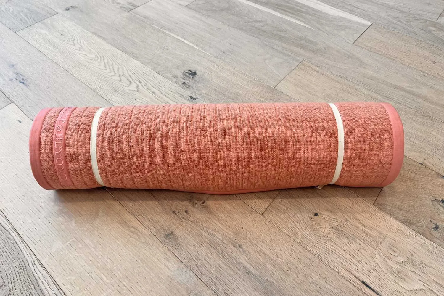 Bella Rose natural non-slip yoga mat rolled on wood floor
